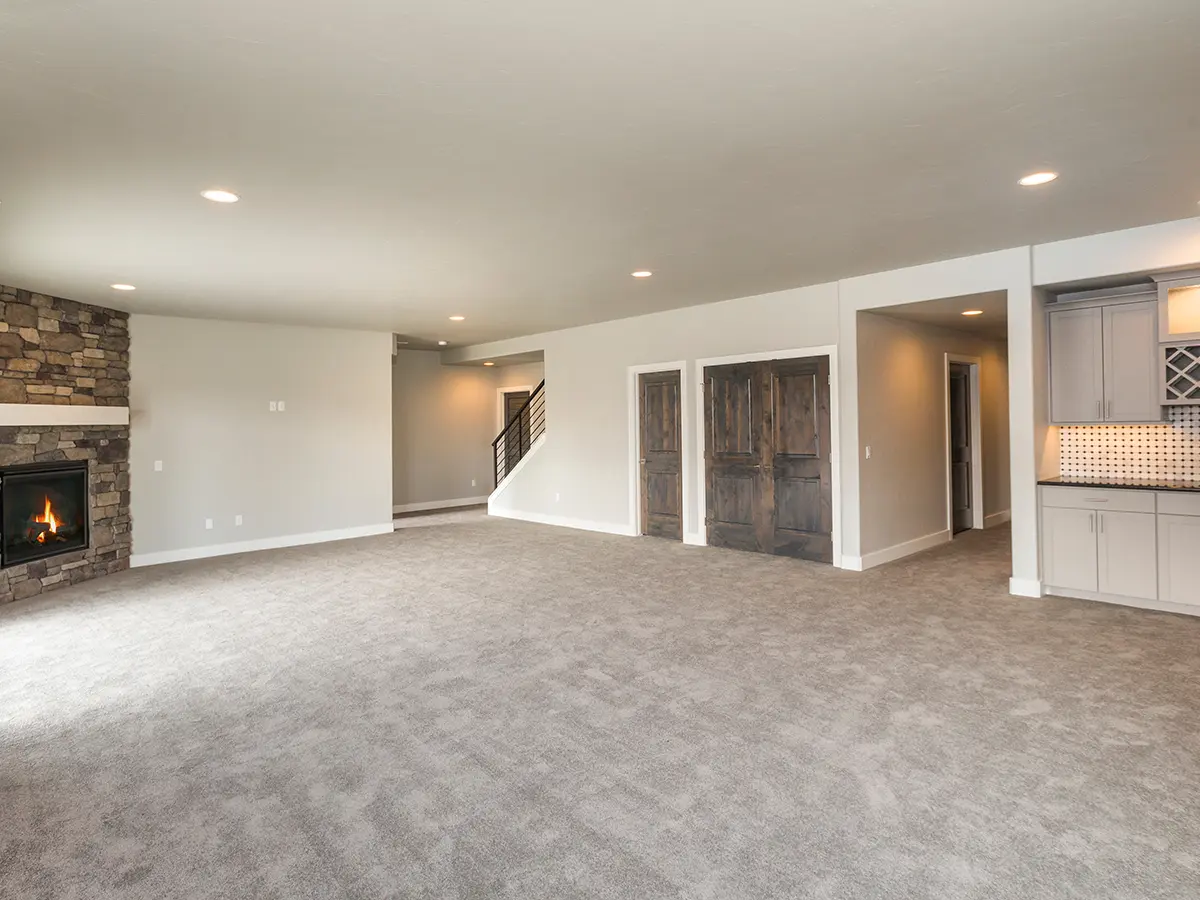 A large basement with carpet flooring and a brick fireplace