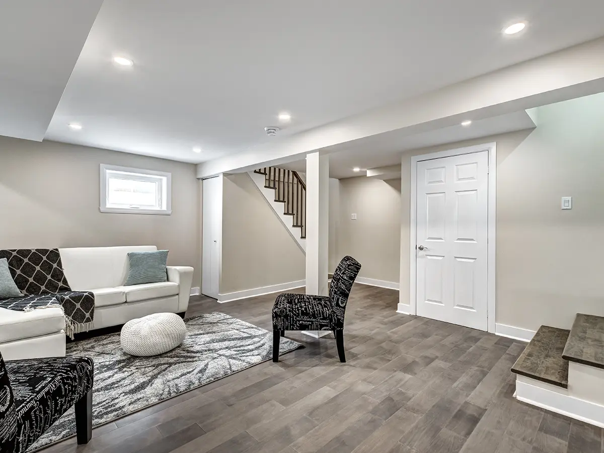 A basement with LVP flooring and black and white furniture