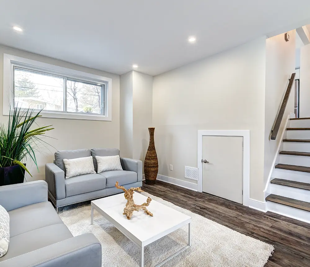 A basement with luxury vinyl plank flooring and two small couches and a table