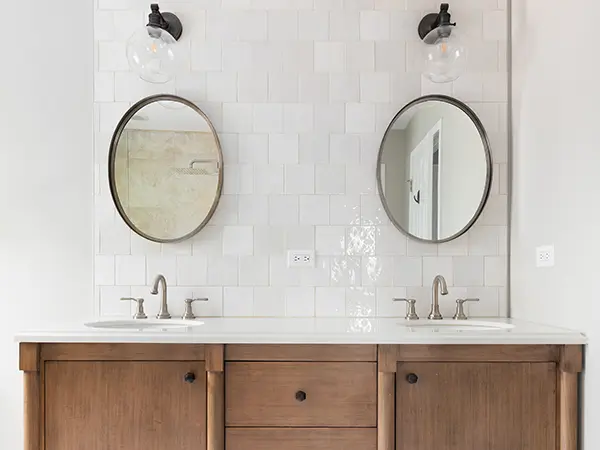 A double vanity with a tile backsplash and two round mirrors