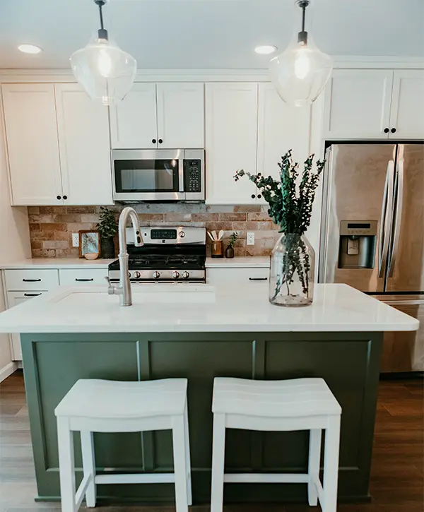 A green kitchen island with pendant lights