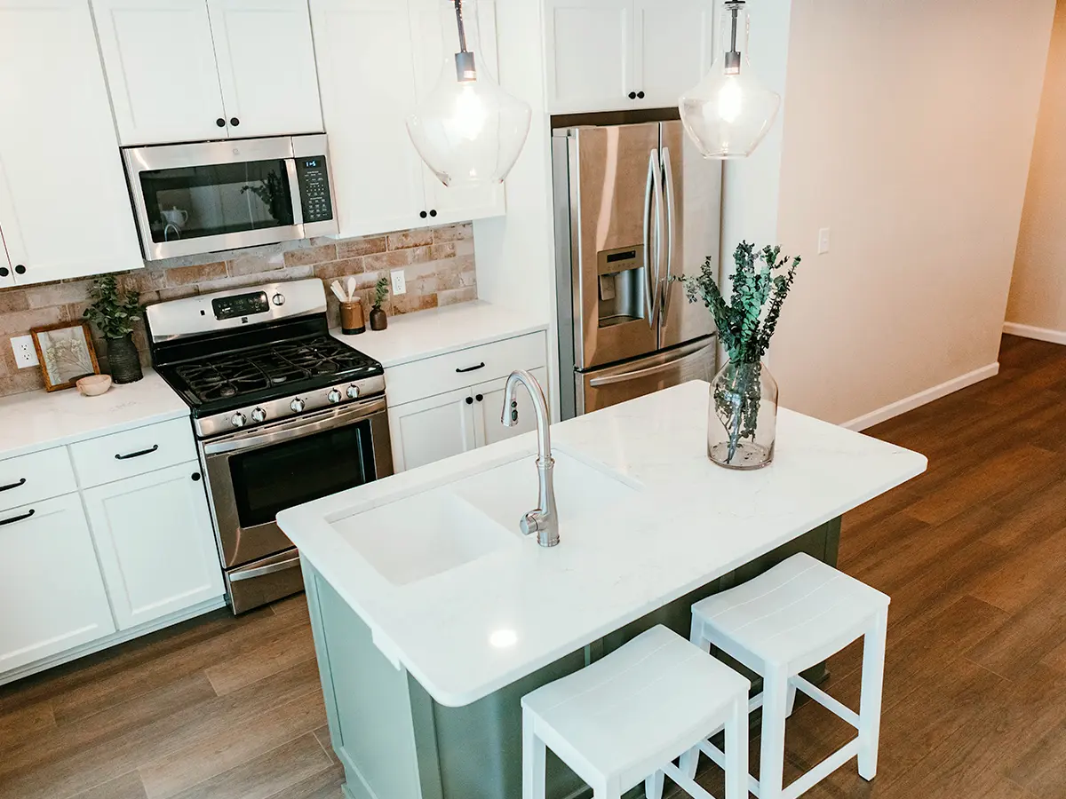 A kitchen with white cabinets and small green island