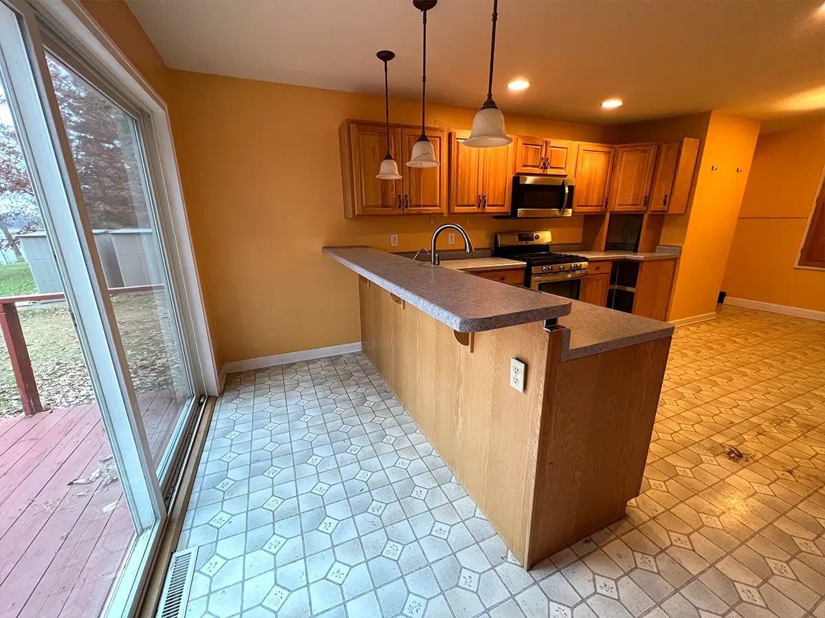 An old kitchen with wood cabinets and linoleum floor