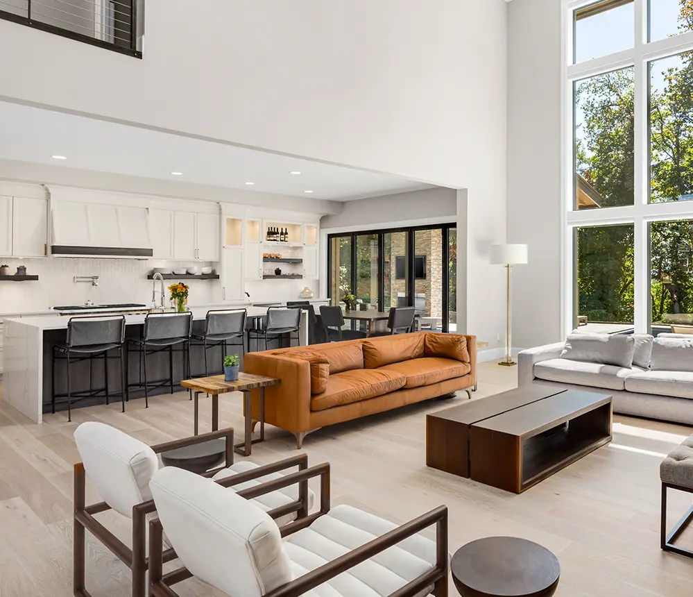 An orange couch in an open space kitchen with large windows and french doors