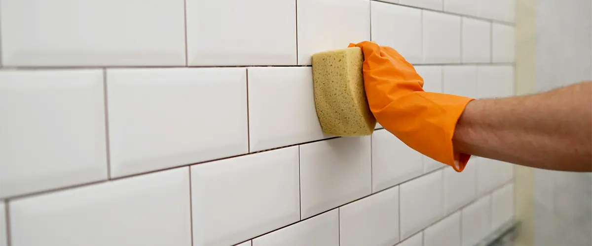 Homeowner cleaning tiles in a shower with a squeegee