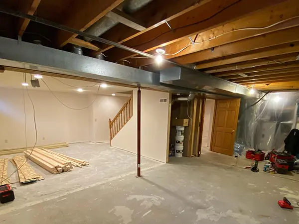 A basement finishing project with lumber pieces spread on the concrete subfloor
