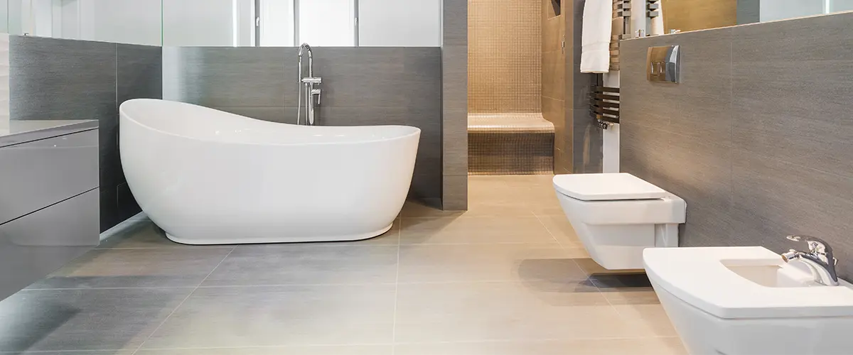 A large bathroom with a freestanding tub and gray tile walls