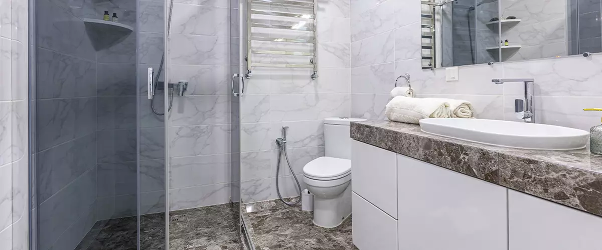 Interior of a modern bathroom with shower, in a small apartment, with white marble tiles