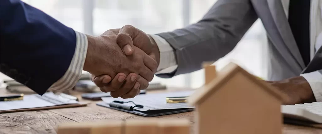 Hiring a general contractor, sales representative shakes hands with a customer and offers a home purchase contract to purchase the current home and a proposed lease for the homeowner