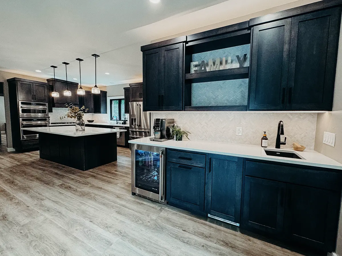 Modern kitchen remodel with dark cabinetry, large island, and stainless steel appliances.