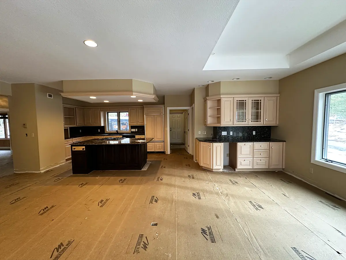 Before kitchen renovation with beige cabinets and bare flooring in progress.