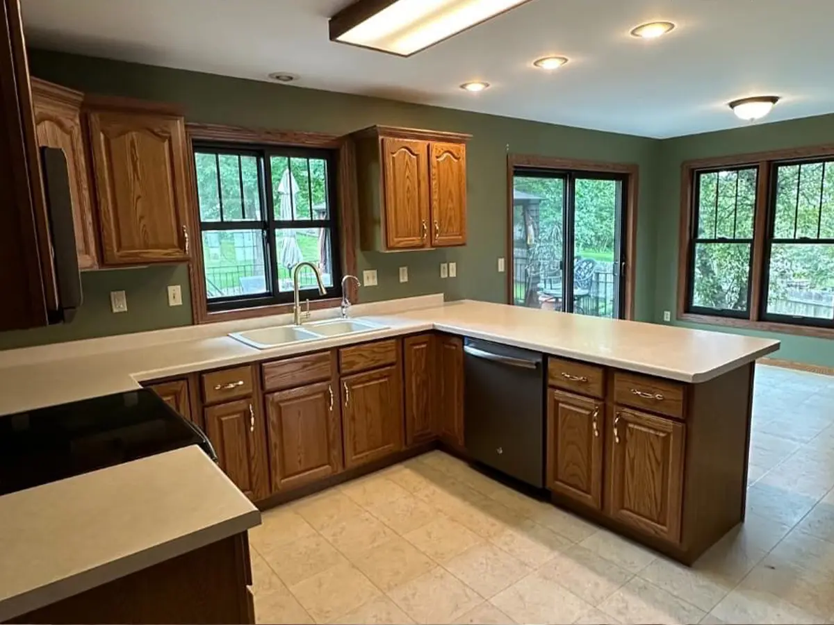 Spacious kitchen with wooden cabinets and tiled flooring before remodeling