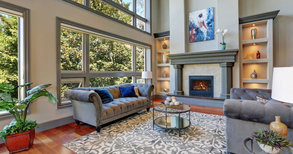 Spacious living room with large energy-efficient windows, modern fireplace, hardwood flooring, and stylish decor