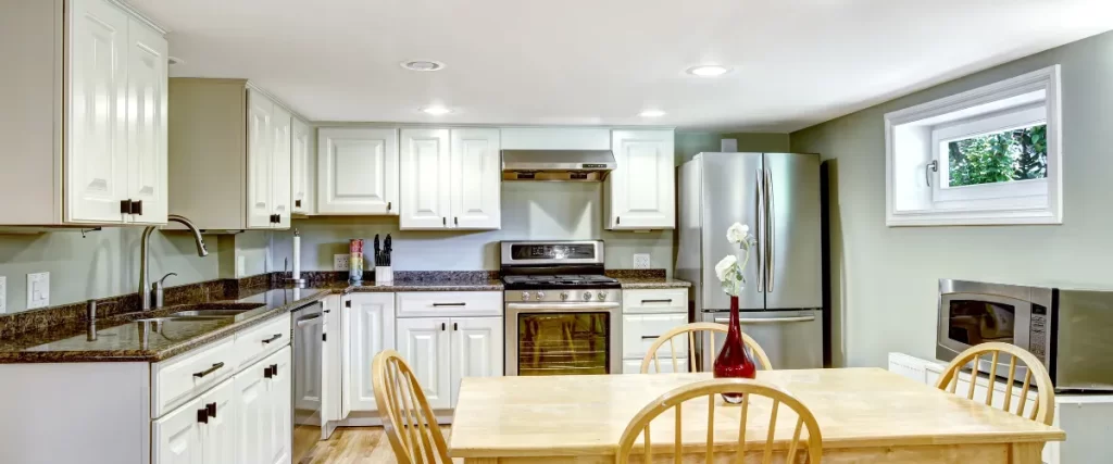 A kitchen with cream-colored cabinets, stainless steel appliances, and a wooden dining table with chairs.