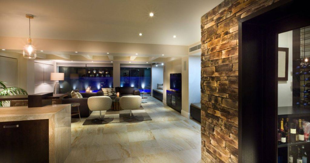 Contemporary basement lounge with stone accent wall and ambient lighting