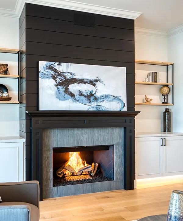 Modern fireplace with black shiplap accent wall and built-in shelving in remodeled living room