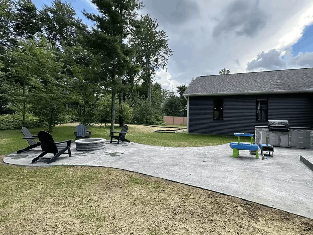 Completed home addition with black siding, stamped concrete patio, and fire pit built by Remodeling Journey in Central Wisconsin