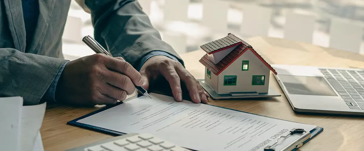 Businessman's signature on documents, checks, and documents in real estate investment projects on the desk. Sales report on the mortgage agent market in real estate concepts