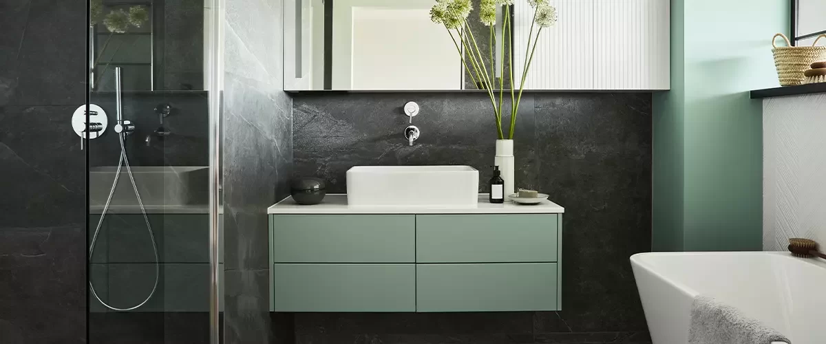 Stylish and creative minimalistic small bathroom interior design with marble walls with green panels, plants and beautiful bathroom accessories